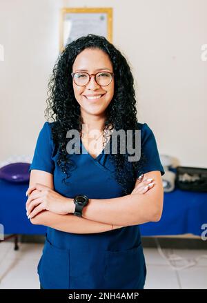 Portrait de femme souriante physiothérapeute. Femme thérapeute physique afro-américaine à bras croisés. Femme souriante chiropracteur en uniforme avec les bras Banque D'Images