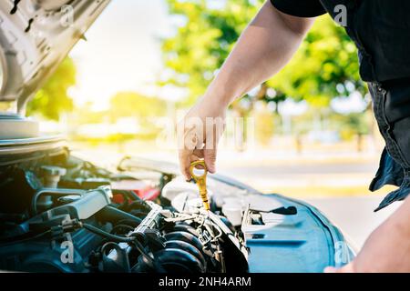 Homme vérifiant l'huile à la main dans la voiture avec l'espace de copie. Des personnes inspectent le niveau d'huile de la voiture à la main. Inspection manuelle du niveau d'huile du véhicule par le conducteur Banque D'Images