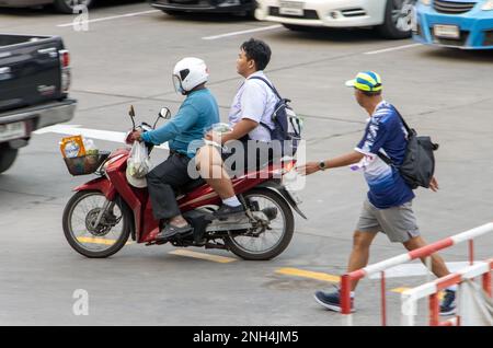 SAMUT PRAKAN, THAÏLANDE, 03 2023 FÉVRIER, Un homme roule avec un garçon en uniforme scolaire sur une moto. Banque D'Images