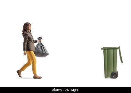 Photo pleine longueur d'une jeune femme vêtue d'un sac de déchets en plastique et marchant vers un bac isolé sur fond blanc Banque D'Images