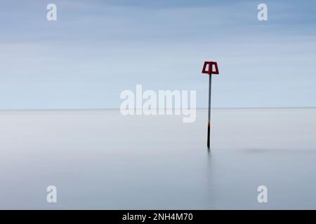 Un marqueur d'aine rouge de défense de plage au milieu d'une mer et d'un ciel parfaitement calmes (paysage) Banque D'Images