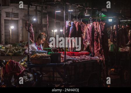 Une belle jeune boucherie cambodgienne vend du bœuf cru la nuit. Le principal marché de gros de la viande, Phsar Dumkor. Phnom Penh, Cambodge. © Kraig Lieb Banque D'Images