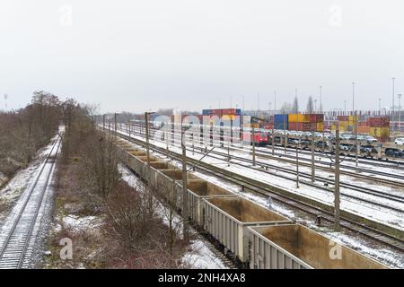 Gare de déchargement et de chargement de fret. Sur la plate-forme il y a des wagons avec des voitures, des wagons vides, des conteneurs déchargés à proximité sur la plate-forme. Banque D'Images