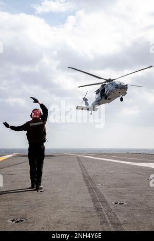 221214-N-WU964-1215 MER DES PHILIPPINES (14 décembre 2022) Airman Brendan Lenhard, mécanicien de structures aéronautiques de Colorado Springs, Colorado, dirige un MH-60s Sea Hawk, attaché au Golden Falcons of Helicopter Sea combat Squadron (HSC) 12, qui se prépare à atterrir sur le pont de vol des États-Unis Le seul porte-avions de la Marine, le USS Ronald Reagan (CVN 76), en mer des Philippines, décembre 14. Le HSC 12, établi à l'origine sous le nom d'Escadron anti-sous-marin d'hélicoptères (HS) 2 sur 7 mars 1952, est le plus ancien escadron d'hélicoptères de la Marine opérationnelle. Ronald Reagan, le navire amiral de Carrier Strike Banque D'Images