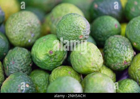 Gros plan plein cadre sur une pile de limes kaffir (Citrus hystrix) sur un stand de marché. Banque D'Images