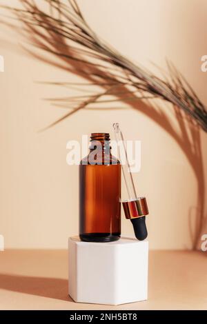 Bouteille de sérum cosmétique marron sur un podium en plein soleil. Concept de cosmétiques naturels pour les soins de la peau. Gros plan. Banque D'Images