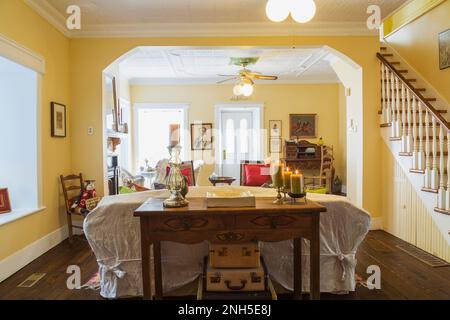 Table de console en bois antique, canapé, chaises éclectiques et bureau de secrétaire avec chaise tissée à dossier haut dans la salle de séjour à l'intérieur de la maison datant de 1830. Banque D'Images