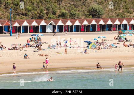 BOURNEMOUTH, Royaume-Uni - 08 juillet 2022. Personnes sur la plage de sable avec rangée de cabines de plage. Bournemouth Beach, Dorset, Royaume-Uni Banque D'Images