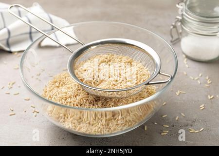 Tamisez avec du riz dans un bol sur une table grise Banque D'Images