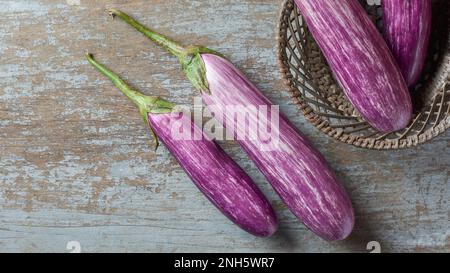 aubergines ou brinjas, également connues sous le nom d'aubergines, légume commun fraîchement récolté sur une surface en bois, prises directement d'en haut avec l'espace de copie Banque D'Images