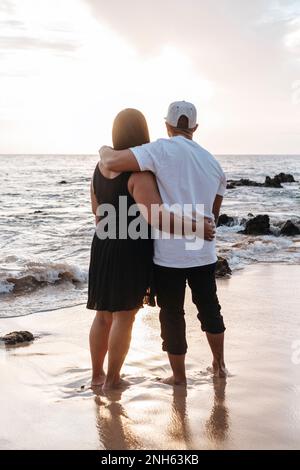 Couple d'hommes et de femmes embrassant tout en regardant le coucher du soleil sur la plage. L'été Banque D'Images