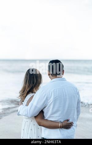 Couple d'hommes et de femmes embrassant tout en regardant le coucher du soleil sur la plage. L'été Banque D'Images