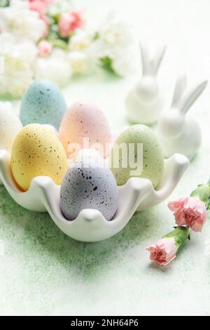 Décor de Pâques. Œufs de Pâques colorés sur un support en céramique et lapins décoratifs. Le concept de préparation de la célébration. Banque D'Images