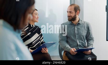 Homme et femme asiatique discutant de l'offre de travail, assis dans le hall et attendant le début de l'entretien d'emploi. Les candidats parlent de carrière professionnelle et de réunion de recrutement. Banque D'Images