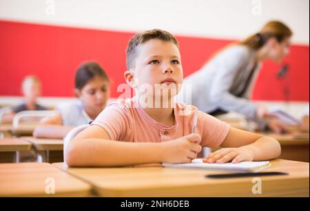 Jeune garçon diligent étudiant avec des camarades de classe à l'école Banque D'Images