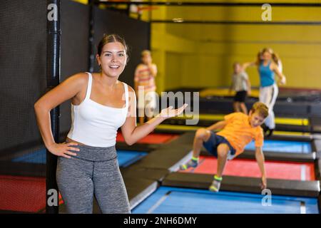 Jeune fille passant du temps avec des enfants dans l'arène de trampoline Banque D'Images