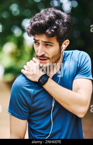 Combattre une blessure à l'épaule. un jeune homme sportif tenant son épaule dans la douleur tout en faisant de l'exercice à l'extérieur. Banque D'Images