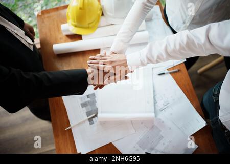 Le travail d'équipe d'architectes et d'ingénieurs se joint à la main, l'ingénieur de construction travaillant sur le chantier, l'ingénieur de construction conceptuel, l'architecte d Banque D'Images