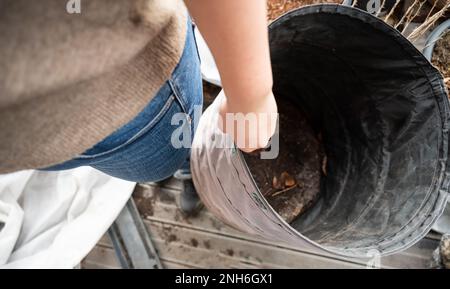 Femme portant une poubelle pliante avec des saletés de jardinage et des branches dans elle sur le balcon, vue à angle élevé Banque D'Images