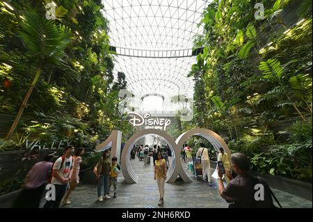 Visiteurs posant pour des photos devant le Rain Vortex et le grand Standee de Disney à l'aéroport de Jewel Changi, février 2023 Banque D'Images