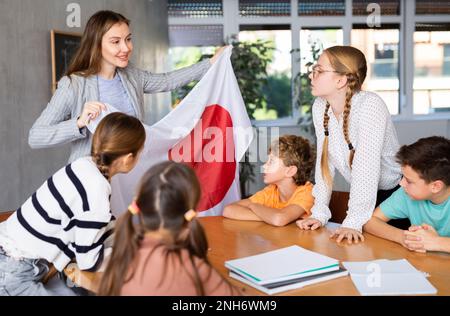 Professeur montrant le drapeau du Japon à un groupe d'écoliers Banque D'Images