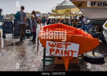 Bateau fraîchement peint avec panneau de peinture humide dans le front de mer de Marsaxlokk, Malte Banque D'Images