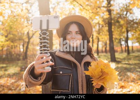 Jeune femme prenant la vidéo pour vlog dans le parc d'automne. Influenceur blogueur féminin enregistrant du contenu pour un journal quotidien sur la nature. Copier l'espace Banque D'Images