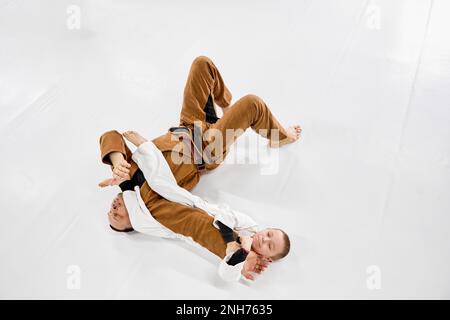 Vue de dessus. Portrait dynamique de l'homme, judo professionnel, entraînement de l'entraîneur de jiu-jitsu avec petit garçon, enfant dans un kimono blanc. Passe-temps sportif Banque D'Images