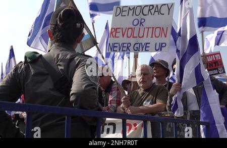 JÉRUSALEM, ISRAËL - FÉVRIER 20 : les membres de la force de sécurité israélienne surveillent les manifestants anti-gouvernementaux qui détiennent les drapeaux israéliens et un signe qui se lit comme « démocratie ou révolution », Ne jamais abandonner' lors d'une manifestation de masse devant le Parlement israélien (Knesset) contre le premier tour de vote sur le nouveau plan du système judiciaire gouvernemental d'Israël sur 20 février 2023, à Jérusalem, en Israël. Crédit : Eddie Gerald/Alay Live News Banque D'Images