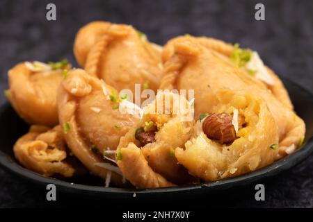 Gujia également appelé Gujiya, Pirukiya, Pirukia, Pedakiya, Karanji, Basundi ou Gughra farci avec Mawa, Khoya, Chasni, Mava, Khoa - Indian Sweet Dumpling Banque D'Images