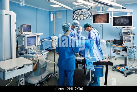 Groupe de chirurgiens concentrés pendant l'opération chirurgicale en salle d'opération avec des infirmières et des assistants Banque D'Images