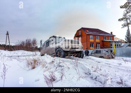 Le SUV blanc russe UAZ Patriot se déplace sur une colline enneigée en hiver. Banque D'Images