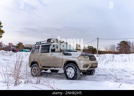 Le 4x4 blanc russe UAZ Patriot se déplace sur une route enneigée en hiver. Banque D'Images