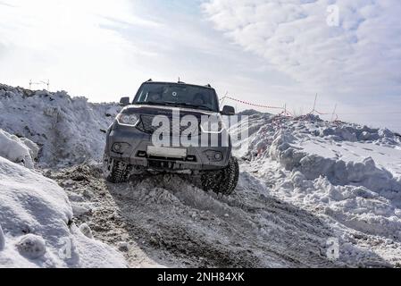 Le SUV russe UAZ Patriot se déplace rapidement sur une route enneigée dans le champ en hiver, s'accrochant à la roue pare-neige. Banque D'Images