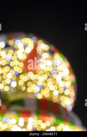 Des bonhomme de neige aux couleurs vives avec une casquette rayée et un foulard, avec des boutons noirs et un nez de carotte ont soulevé une main accueillante dans des gants. Banque D'Images