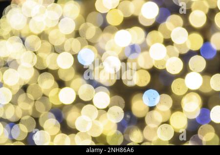 Le bokeh. Silhouettes floues de lumières brillantes, de fêtes de nouvel an et de décorations de Noël jaune et bleu. Banque D'Images