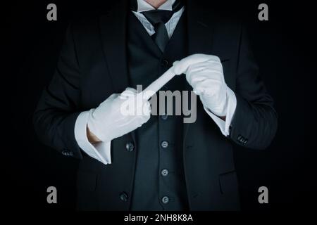 Portrait de Butler en costume sombre et gants blancs faisant un geste grossier. Concept de rébellion Banque D'Images