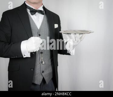 Portrait de Butler ou de garçon en costume sombre habillé tenant plateau argent. Concept de l'industrie des services et de l'accueil professionnel. Banque D'Images