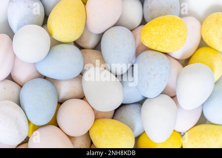 Pile d'œufs de Pâques en chocolat bleu, jaune, rose et blanc aux couleurs pastel. Banque D'Images
