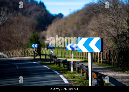 Panneau de route strié bleu vif « virage à gauche » Banque D'Images