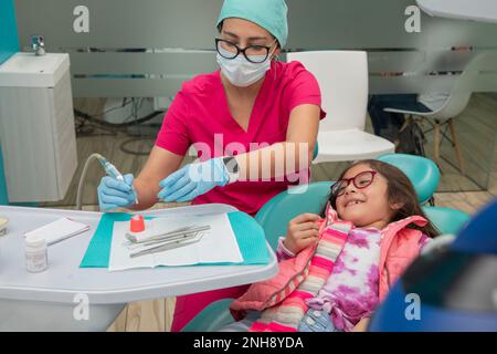 Fille souriant que son dentiste se prépare à donner à ses dents un nettoyage Banque D'Images