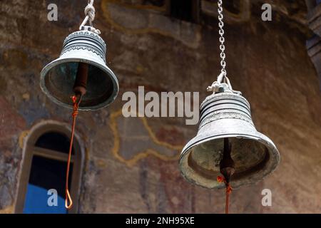 Deux cloches de fer accrochées au plafond de l'église de Dormition avec des fresques médiévales colorées dans le complexe du monastère de la grotte de Vardzia, en Géorgie. Banque D'Images