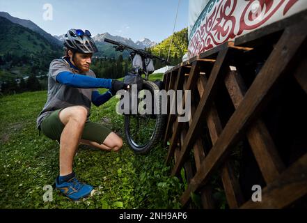 Homme avec des dreadlocks et fermer son sac touristique à vélo de montagne près de la maison Nomad Yurt à Almaty, Kazakhstan. Vélo Extreme Sport, bikepacking et out Banque D'Images