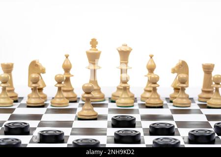 jouer selon différentes règles sur la même carte - les pions noirs et les figures d'échecs blanches sur l'échiquier noir blanc, le disque de pions noirs attaque la patte blanche Banque D'Images