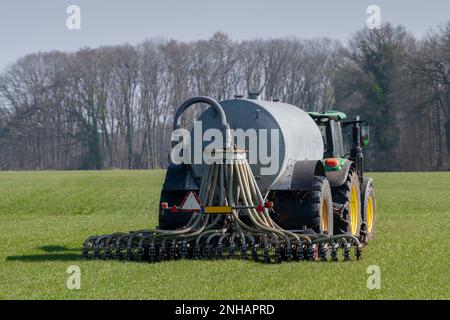 Tracteur vert avec un camion de fumier sur un champ d'herbe dans l'est des pays-bas au printemps Banque D'Images