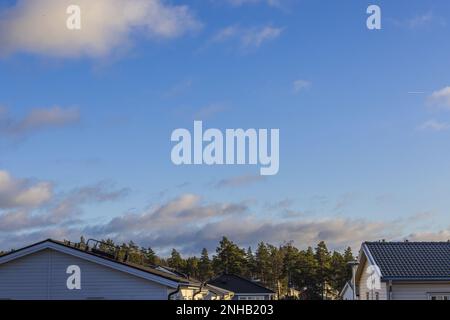 Belle vue sur les toits des villas en bois sur les arbres de forêt verte et le ciel bleu avec des fonds de nuages gris clair. Suède. Uppsala. Europe. Banque D'Images