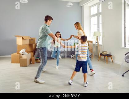 Bonne joie de danser en famille et de s'amuser dans leur nouvel appartement spacieux par jour de déménagement Banque D'Images