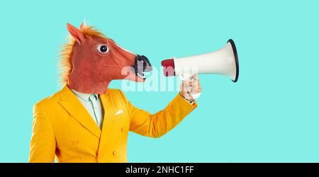 Homme en costume jaune et drôle de masque de cheval parlant à travers le mégaphone sur fond bleu Banque D'Images