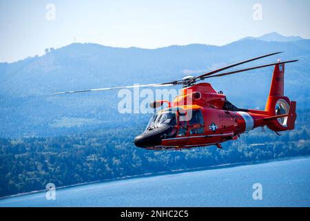 Un équipage d'hélicoptère MH-65 Dolphin effectue un vol de formation au-dessus de Port Angeles, Washington, 28 juillet 2022. La station aérienne est située au bout de la péninsule d'Ediz Hook à Port Angeles. Banque D'Images