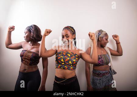 Trois femmes africaines élèvent leur biceps, concept de femmes fortes et habilitées. Banque D'Images